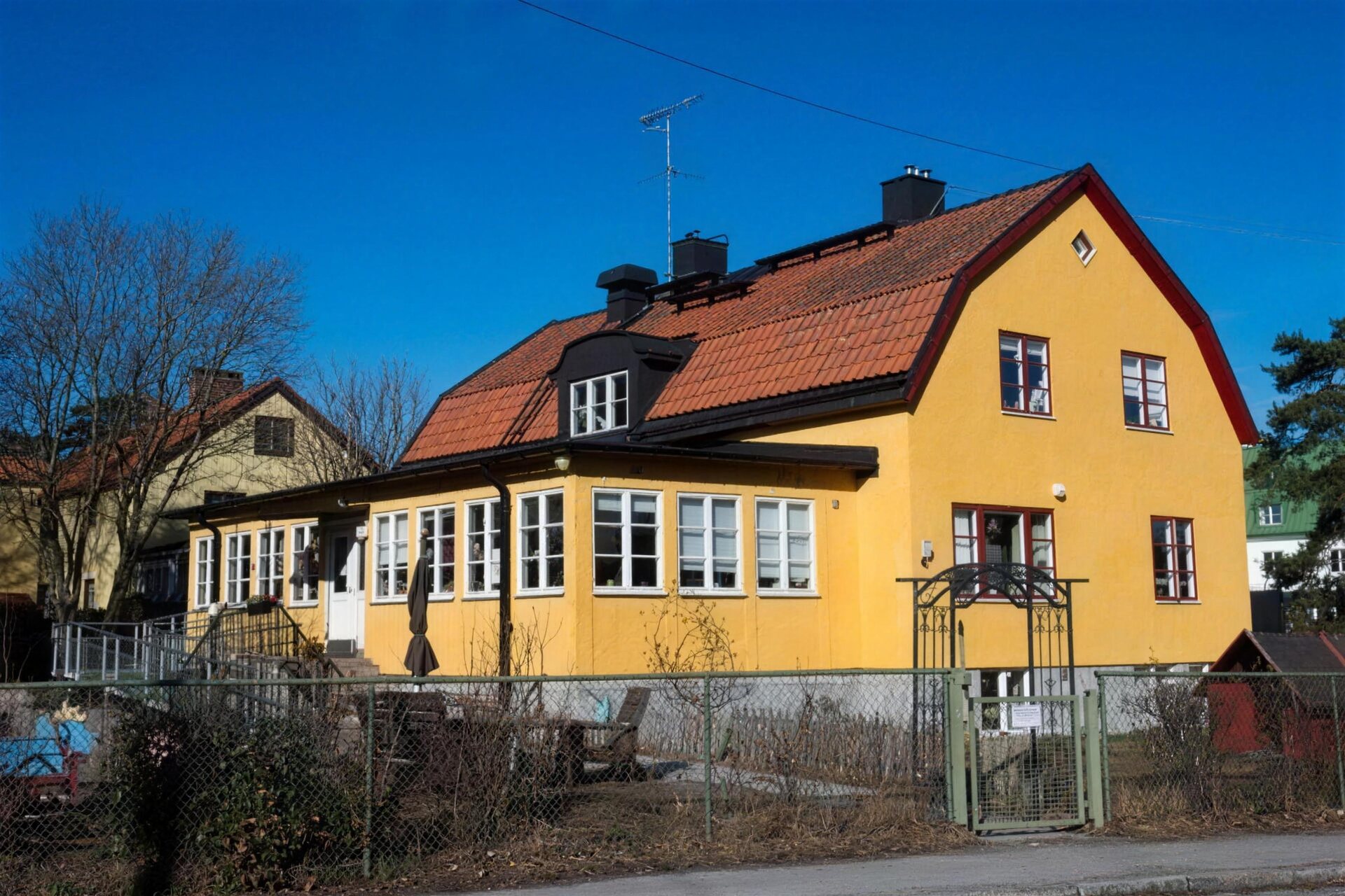 Gul villa med rött tegeltak och vita fönster