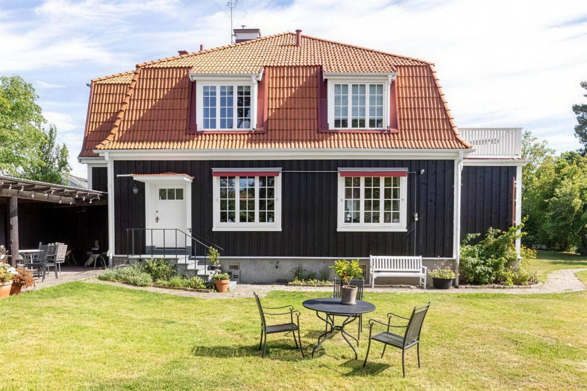Gult trähus med snickarglädje över entrén och nymålade vita fönster