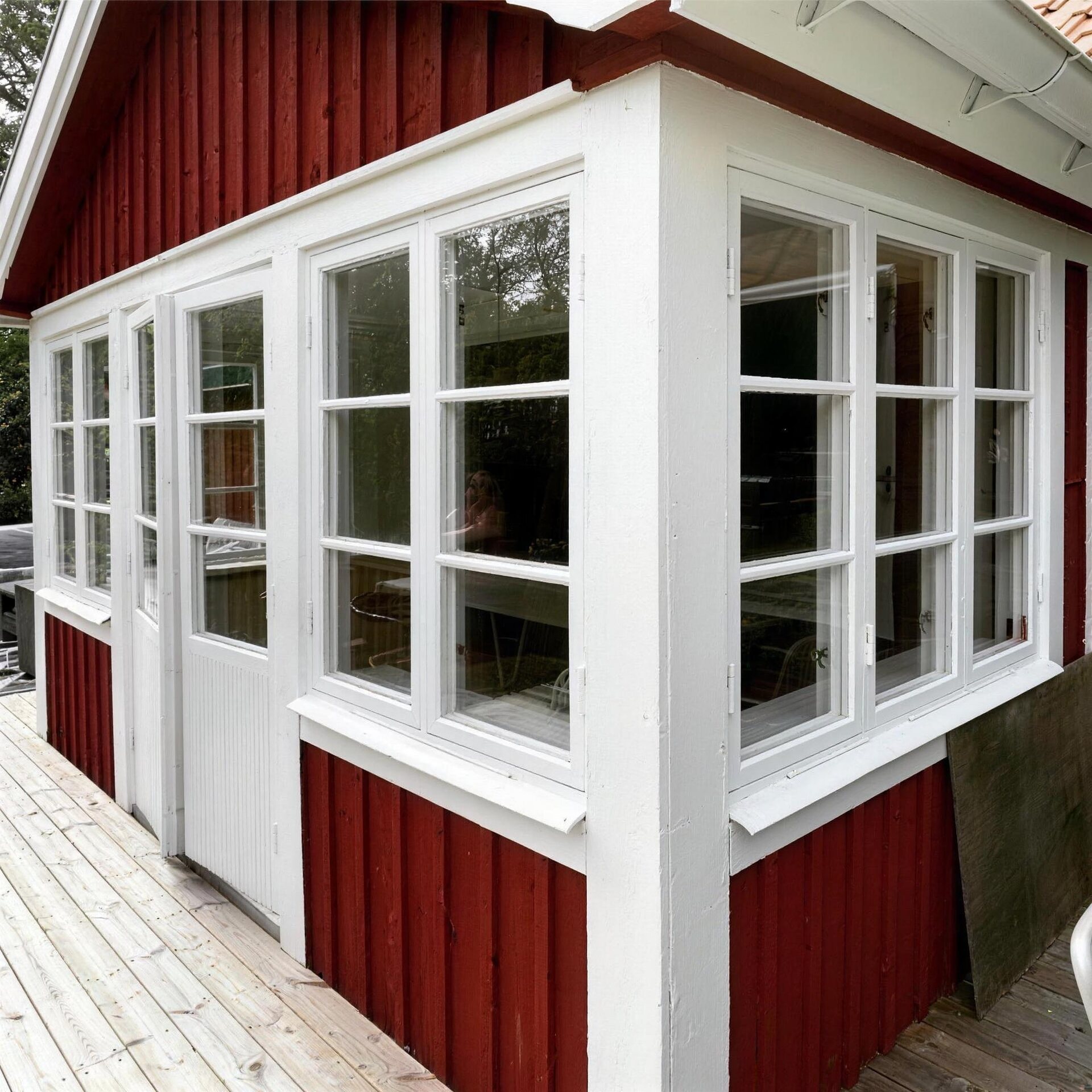 Rött trähus med vita fönster i hörnet