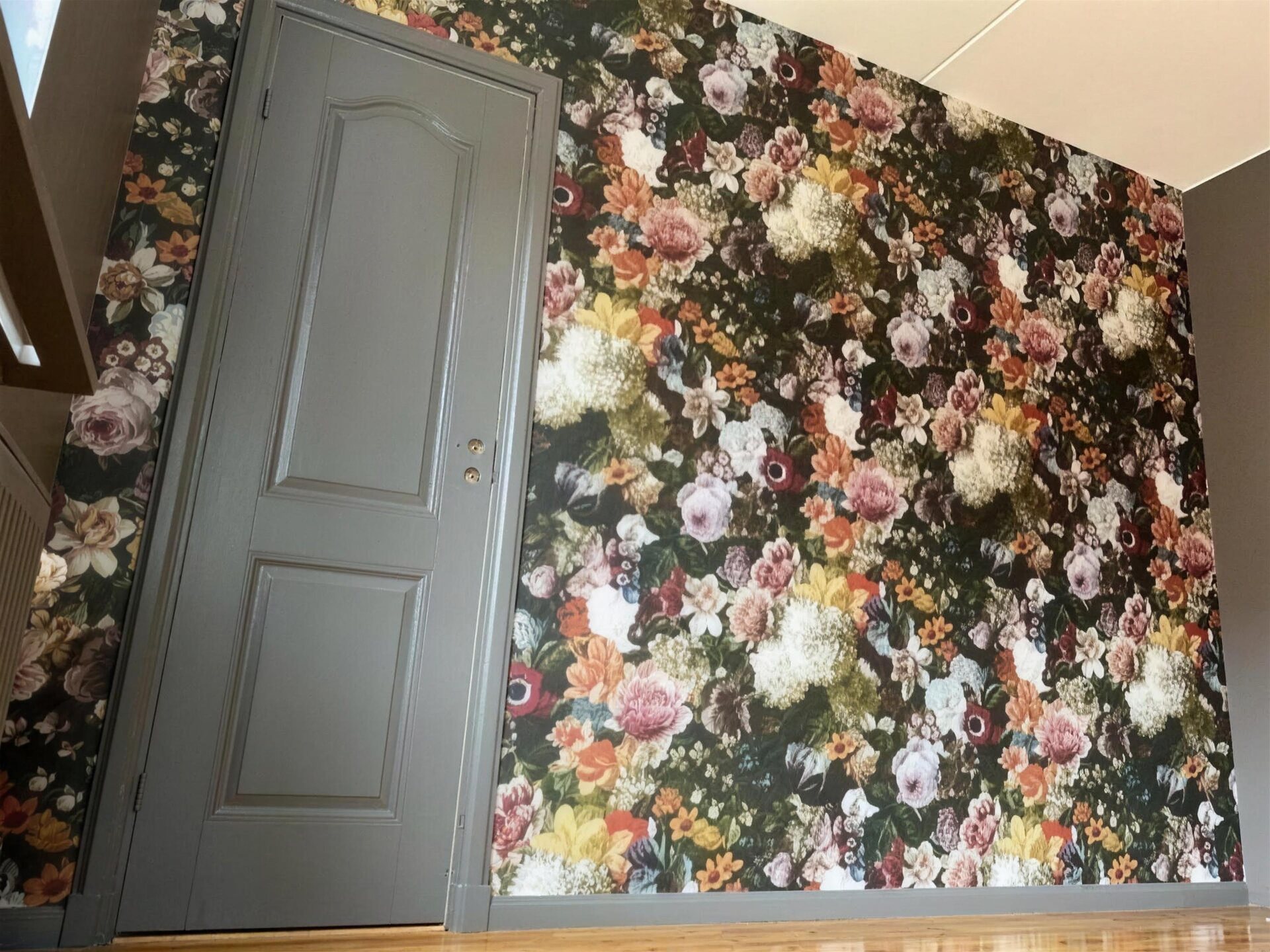 Blommig tapet och grå dörr
